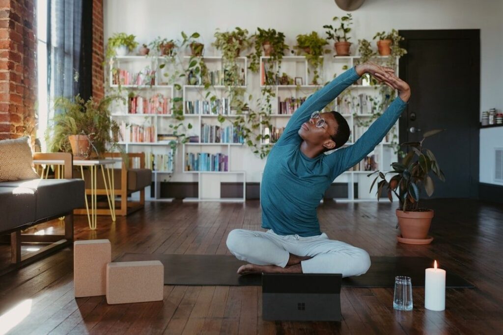 Person sitter på yogamatta och sträcker armarna åt sidan i ett ljust hem